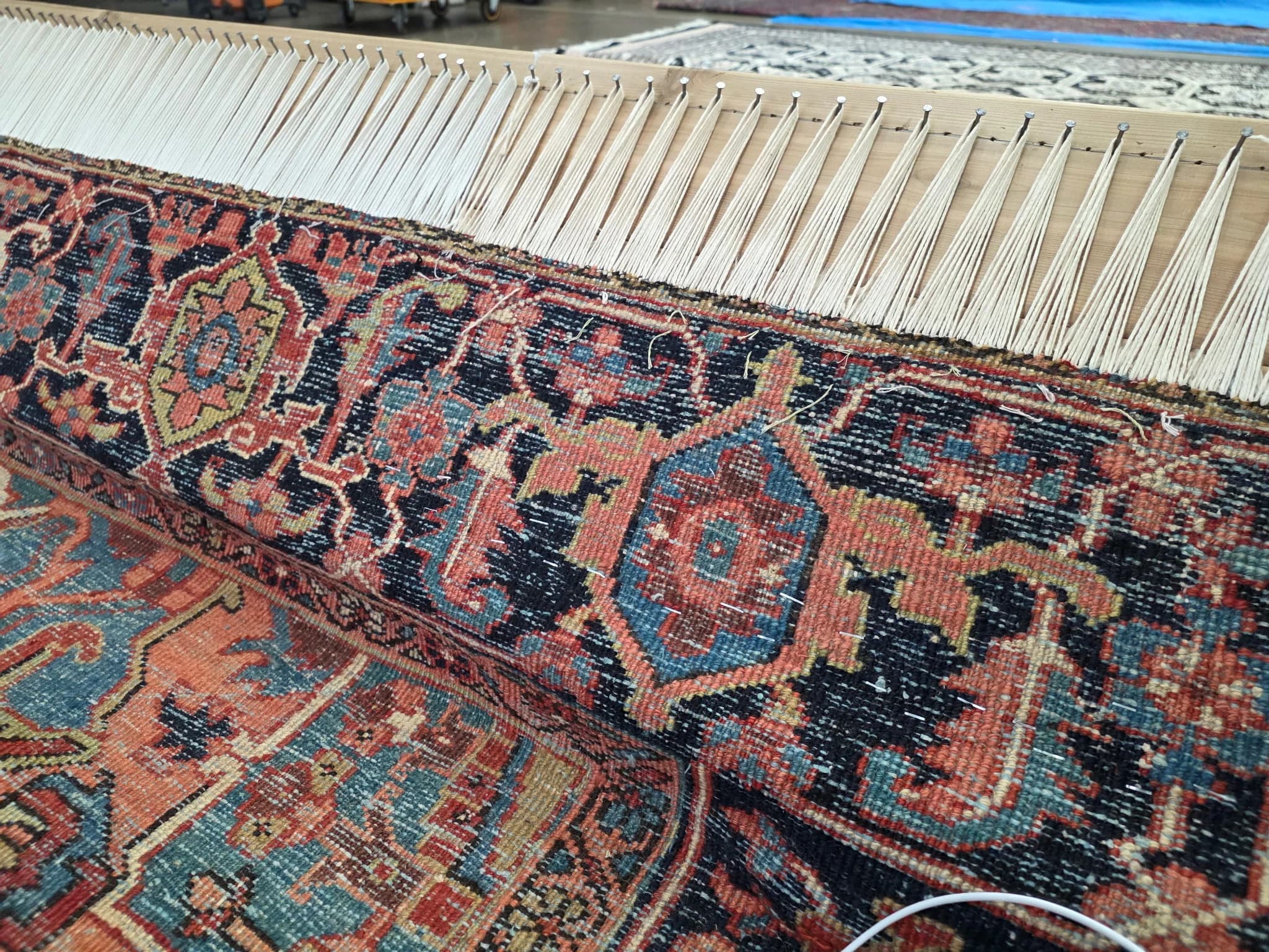 Worn, unravelling end of an antique Persian rug with exposed warp threads before reconstruction — Ahmadi Rug, Skokie IL