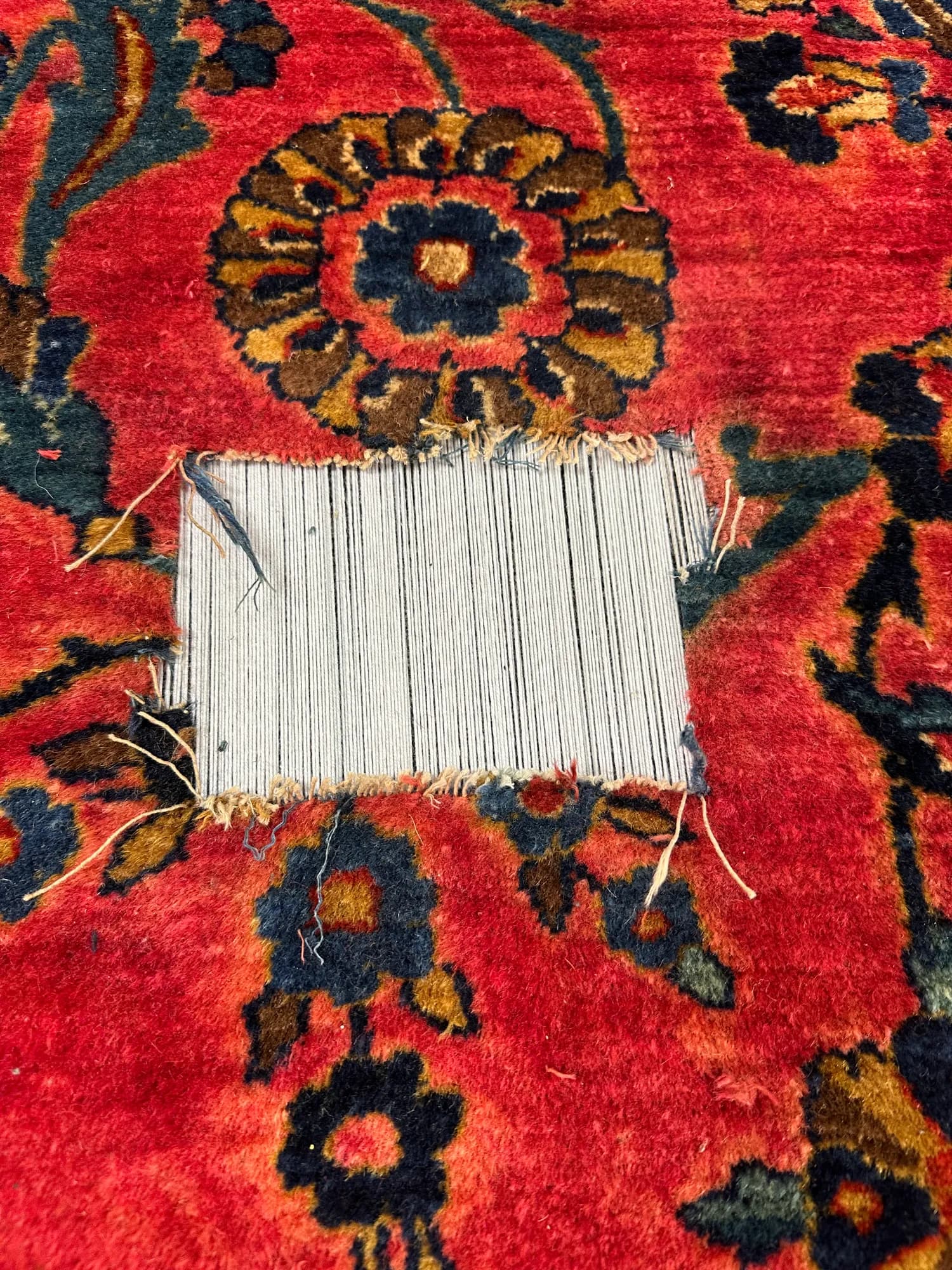 Red Sarouk rug with a worn hole exposing the foundation before reweaving — Ahmadi Rug, Lincoln Park IL